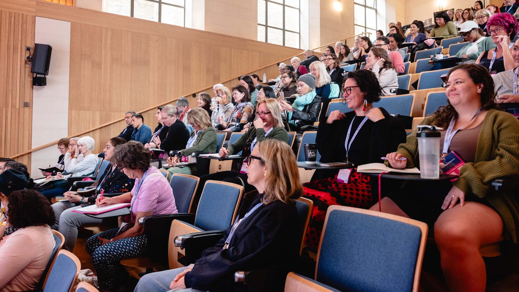 Asistentes sonriendo y tomando notas en el auditorio de Transform Trauma Oxford
