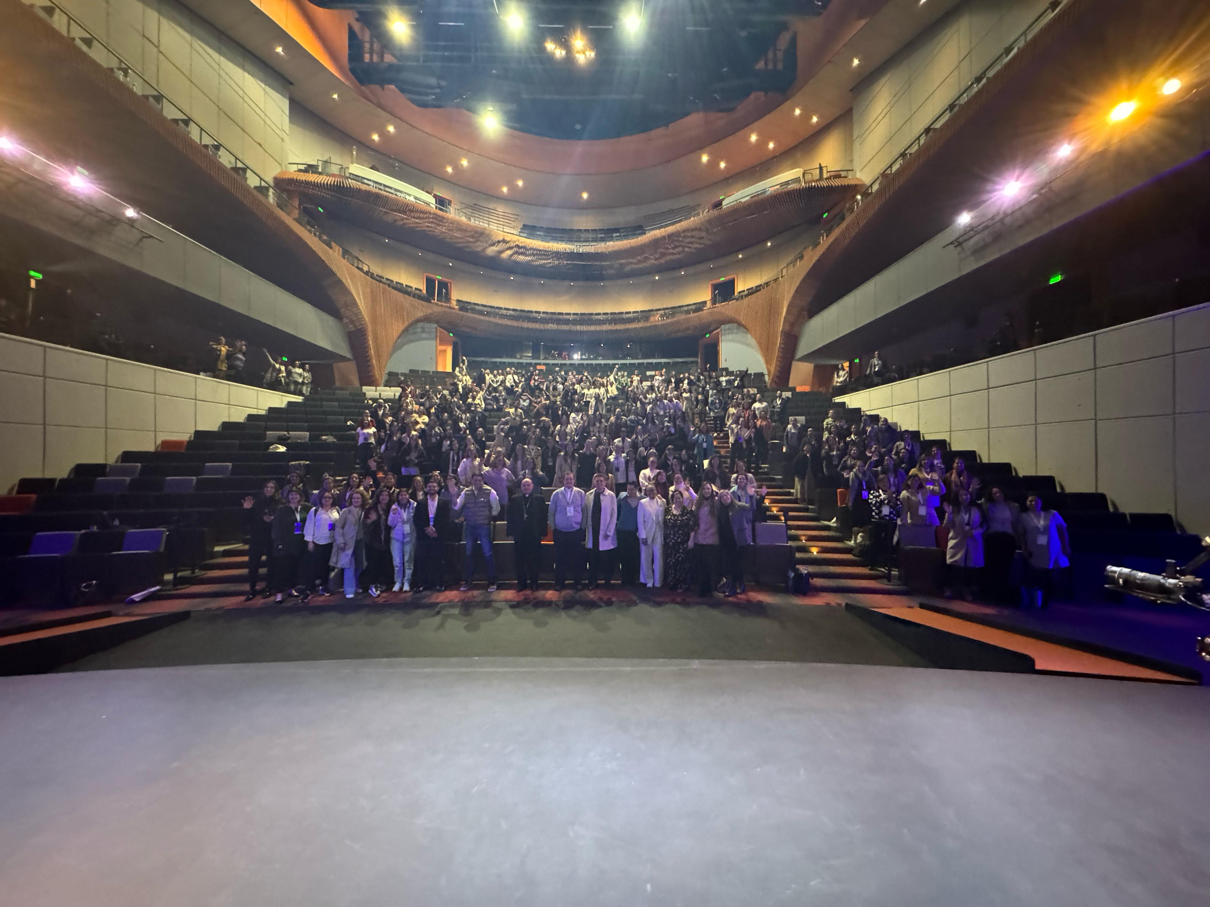 Vista desde el escenario del auditorio de la Universidad Anáhuac lleno de asistentes saludando