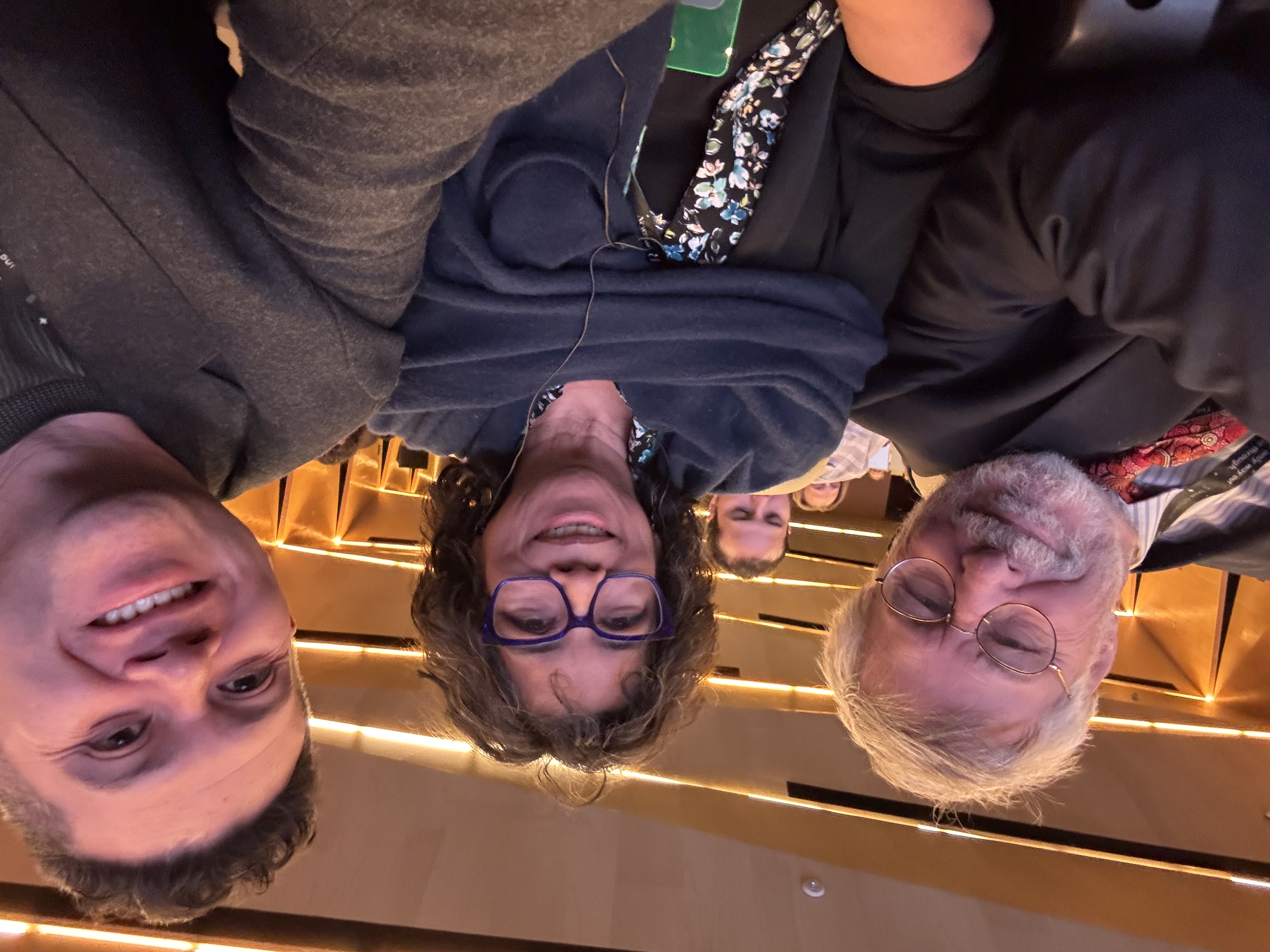 Oscar Rivas en una selfie junto a dos colegas dentro de un auditorio durante una conferencia
