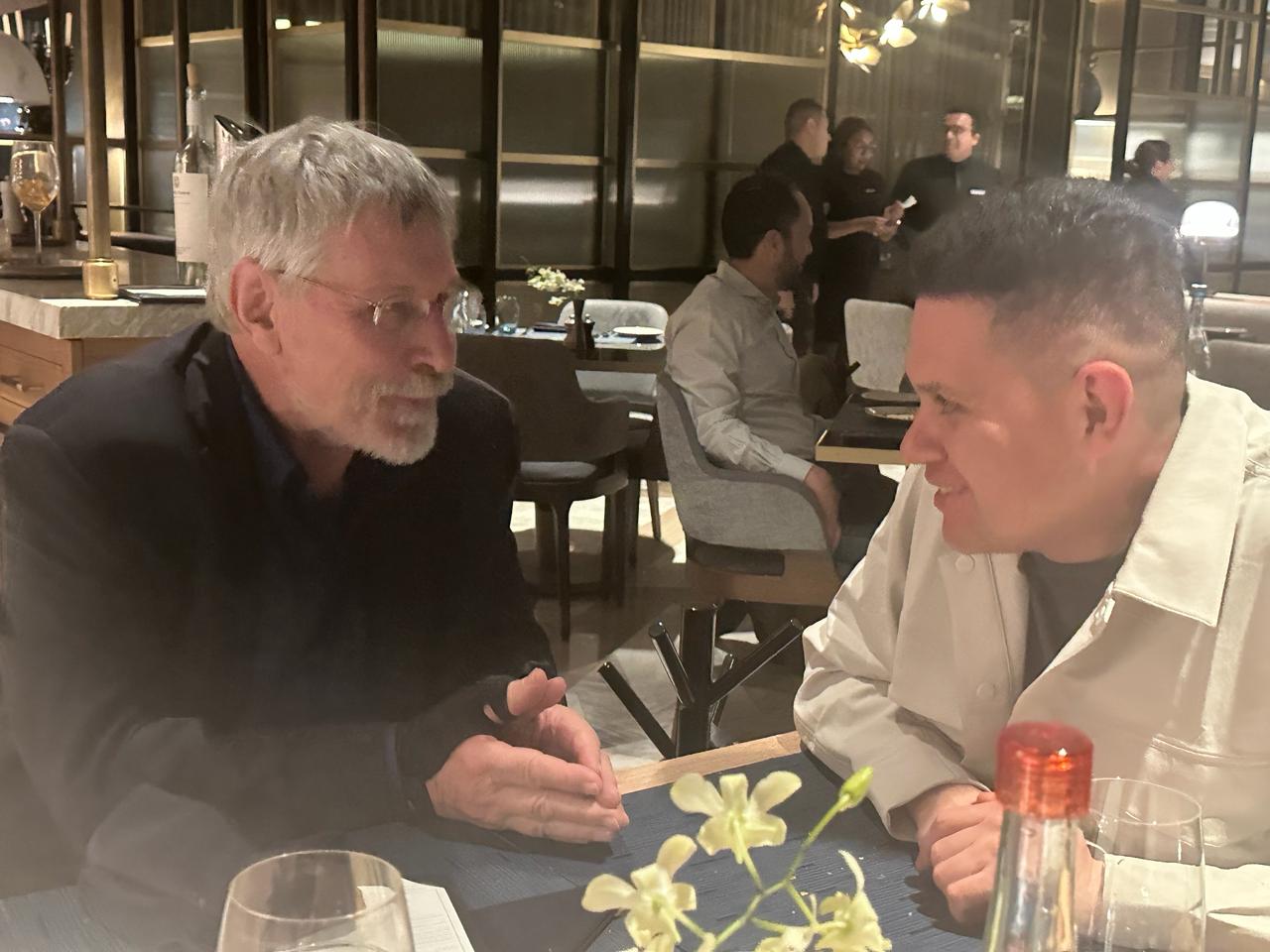 Oscar Rivas conversando de cerca con un referente internacional durante una cena