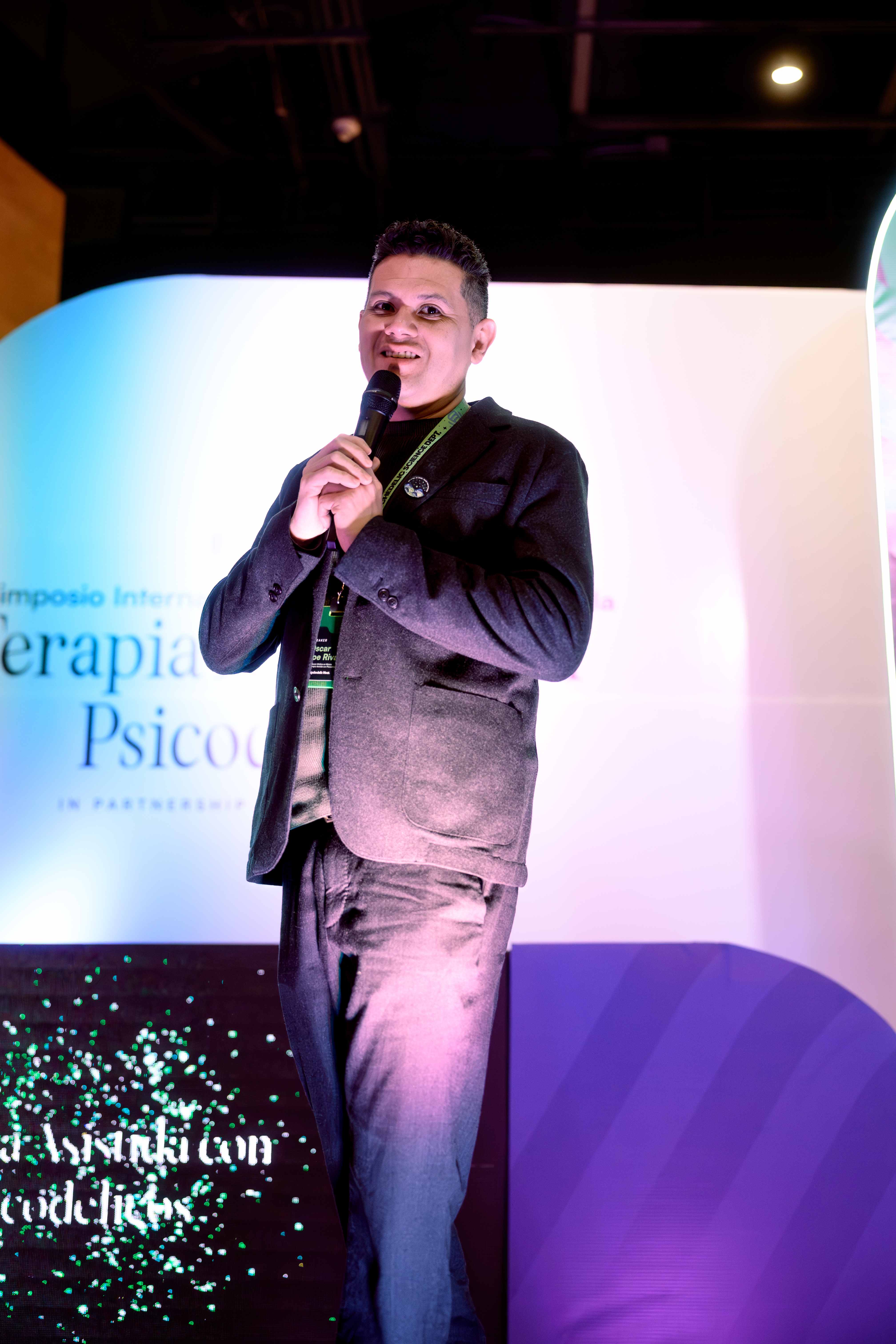 Oscar Rivas con micrófono sobre el escenario del Simposio Internacional Médico de la Terapia Asistida con Psicodélicos