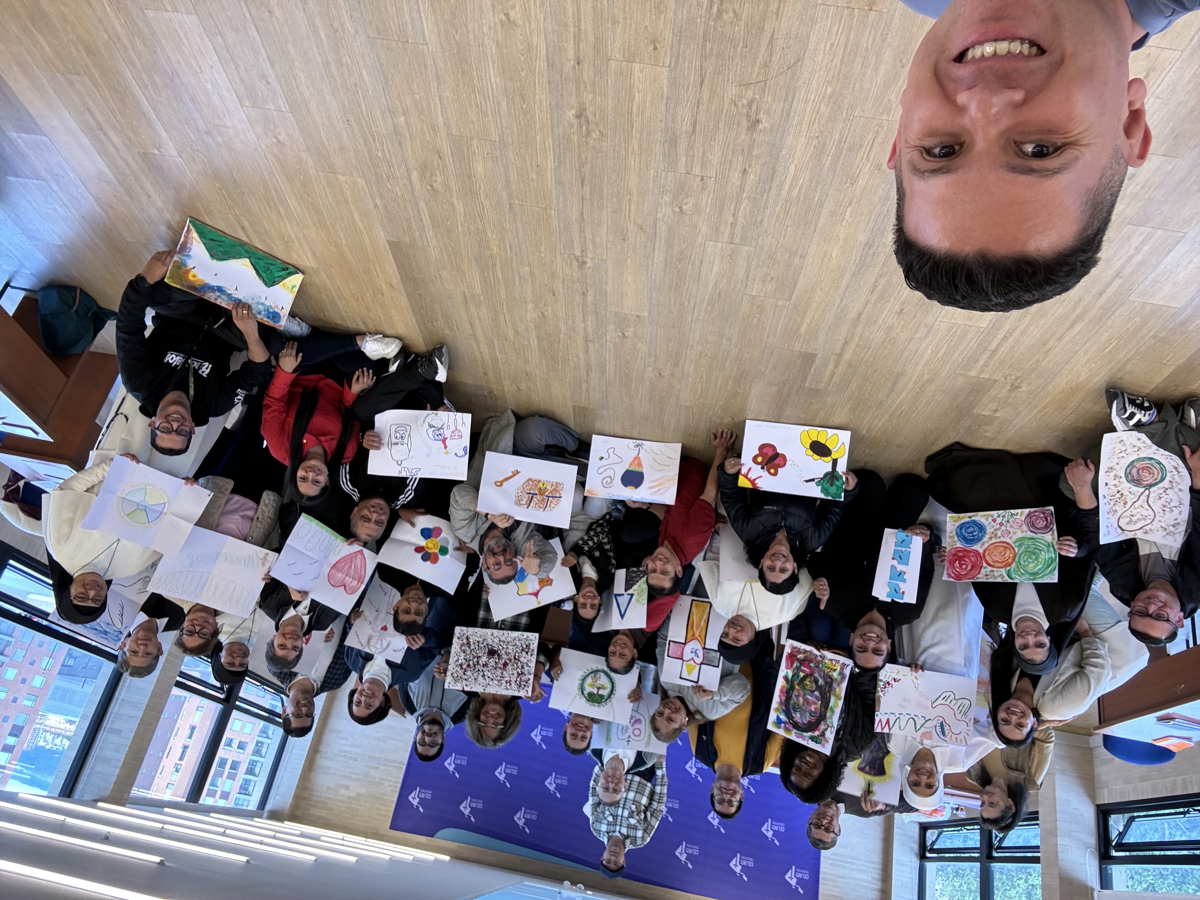 Oscar Rivas en una selfie grupal con los participantes de un taller en el CELAM mostrando sus dibujos